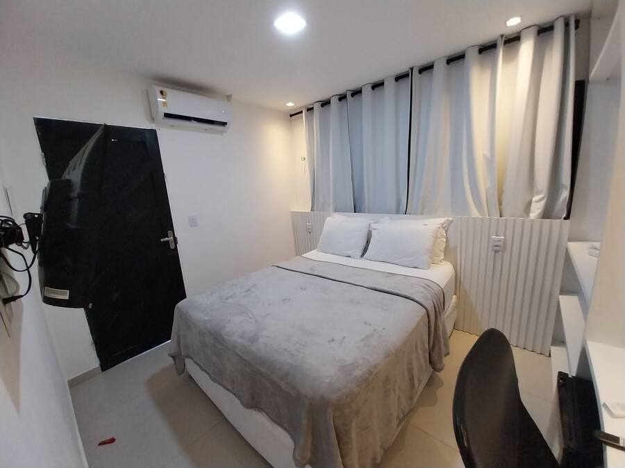 Una camera da letto con un letto, una scrivania, una sedia, un condizionatore d'aria e una porta.