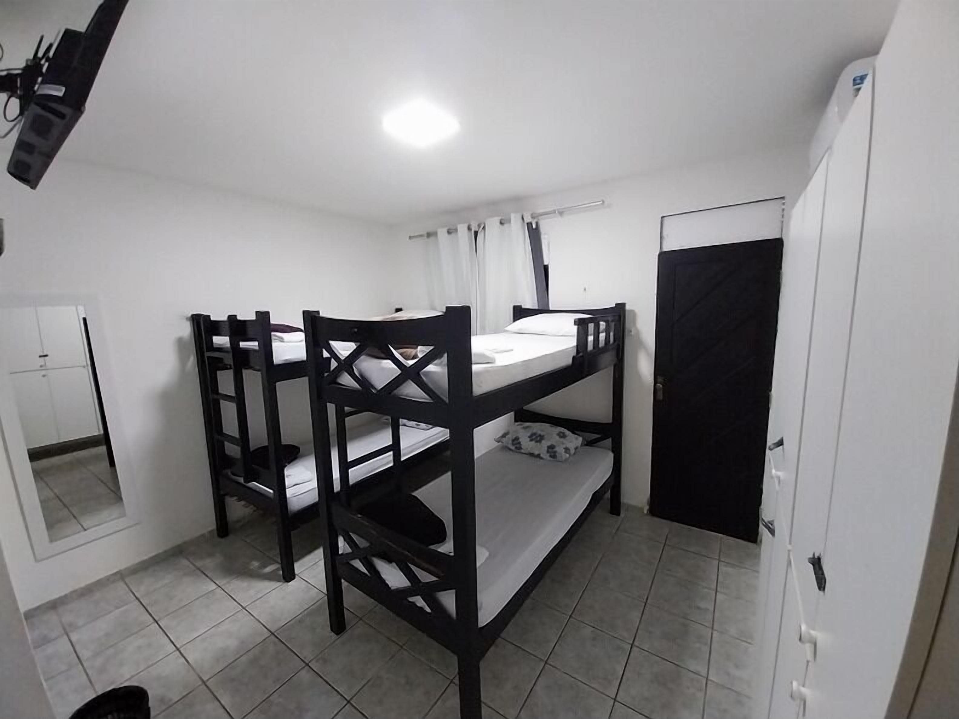 Habitació amb lliteres, un mirall, un armari i una porta.