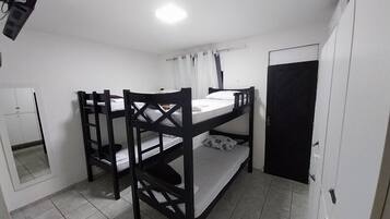 Habitació amb lliteres, un mirall, un armari i una porta.