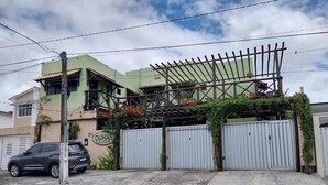 A building with a green facade, a metal gate, and a car parked in front. - Pousada Dunas Natal (Natal)