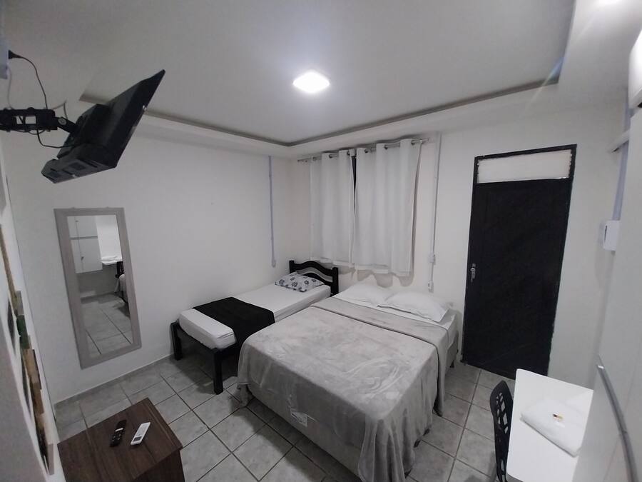 Una habitación pequeña y limpia con dos camas individuales, un escritorio, una silla, un espejo y una puerta.