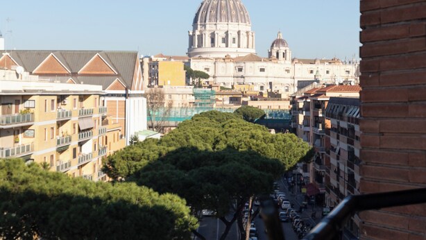 A view of a cityscape with a prominent dome-shaped building in the distance, surrounded by multi-story buildings and trees along the street. - Lovely 3-bedroom apartment with AC in vibrant Roma, 8 sleeps, 2 bathr, balconies (Roma)