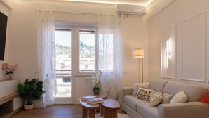 A living room with a sofa, a coffee table, and a small table with a book and a plant. - Lovely 3-bedroom apartment with AC in vibrant Roma, 8 sleeps, 2 bathr, balconies (Roma)