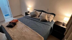Une chambre à coucher avec un lit, des tables de chevet et une commode.