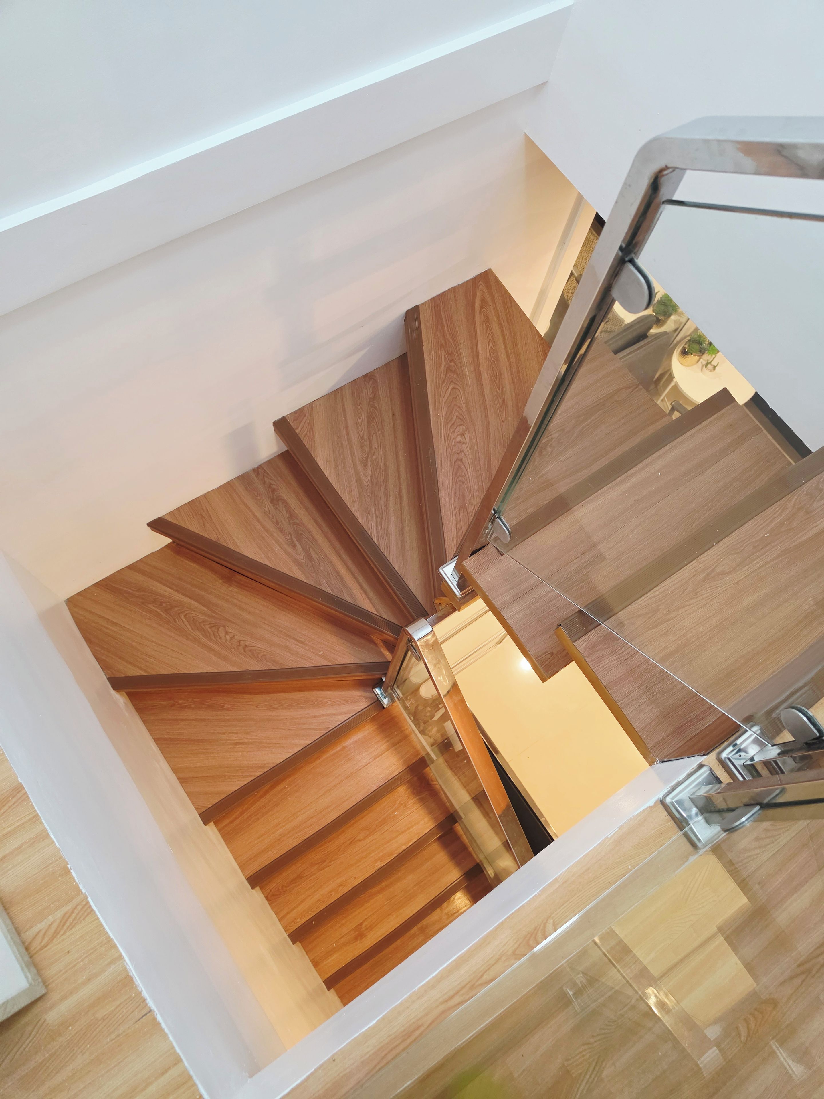 A spiral staircase with wooden steps and a glass railing.