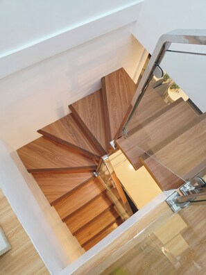 A spiral staircase with wooden steps and a glass railing. - Casa Rosa2 2BR Loft in BGC With 55" Smart TV & 5 pax (Taguig)