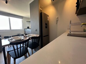 A modern kitchen with a dining area, a refrigerator, and a water dispenser. - Oceana Suites Ñuñoa Central (Santiago)