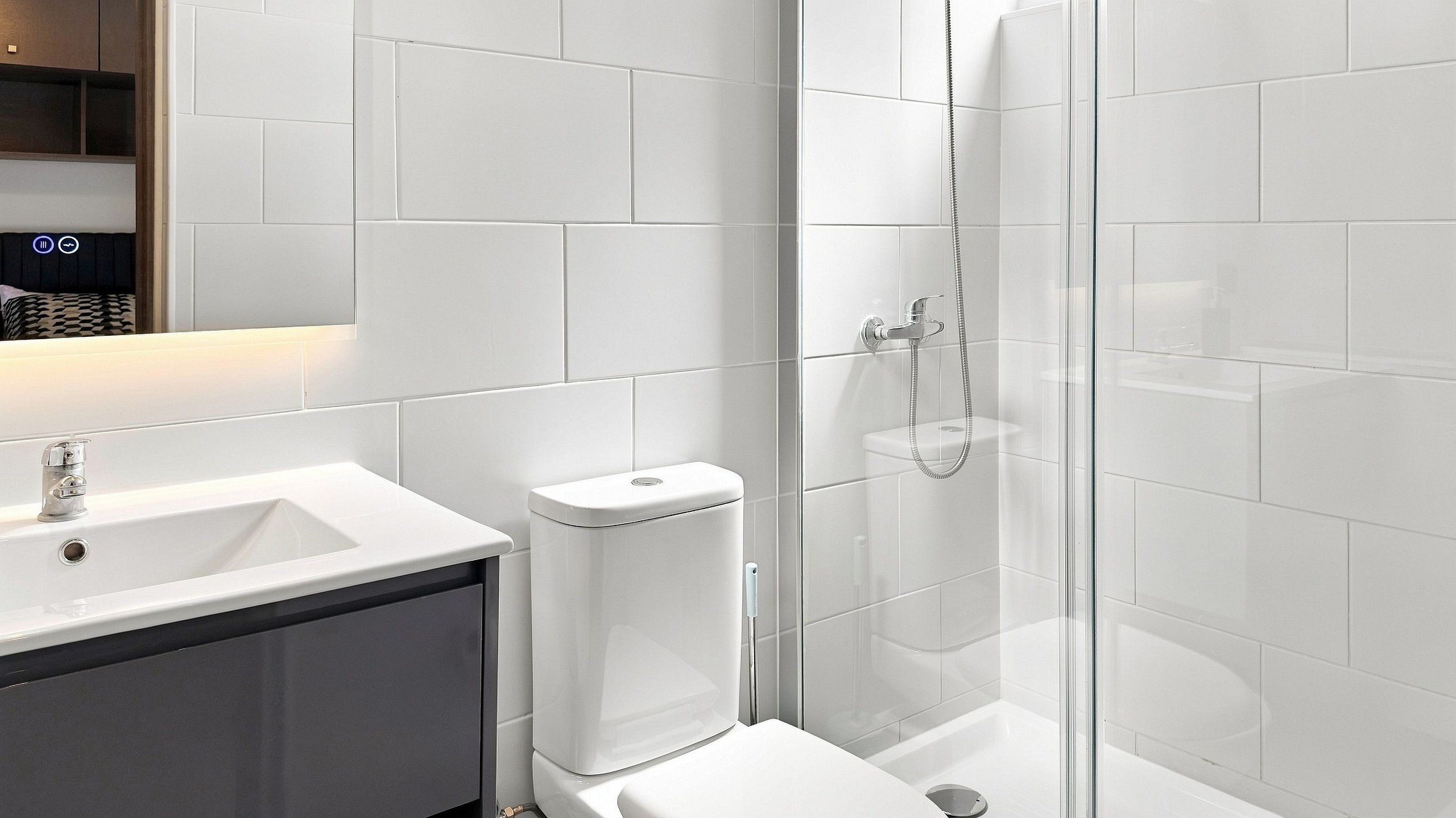 A modern bathroom with a white sink, toilet, and shower area.