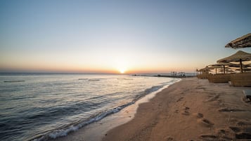 Praia particular, guarda-sóis, toalhas de praia