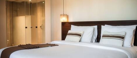 A hotel room with a large bed, a wooden headboard, and a glass shower enclosure.