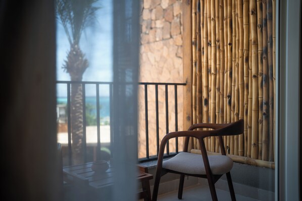A balcony with a wooden chair, a stone wall, and a view of the sea. -  ananea Hurghada – Adults Only (Hurghada)