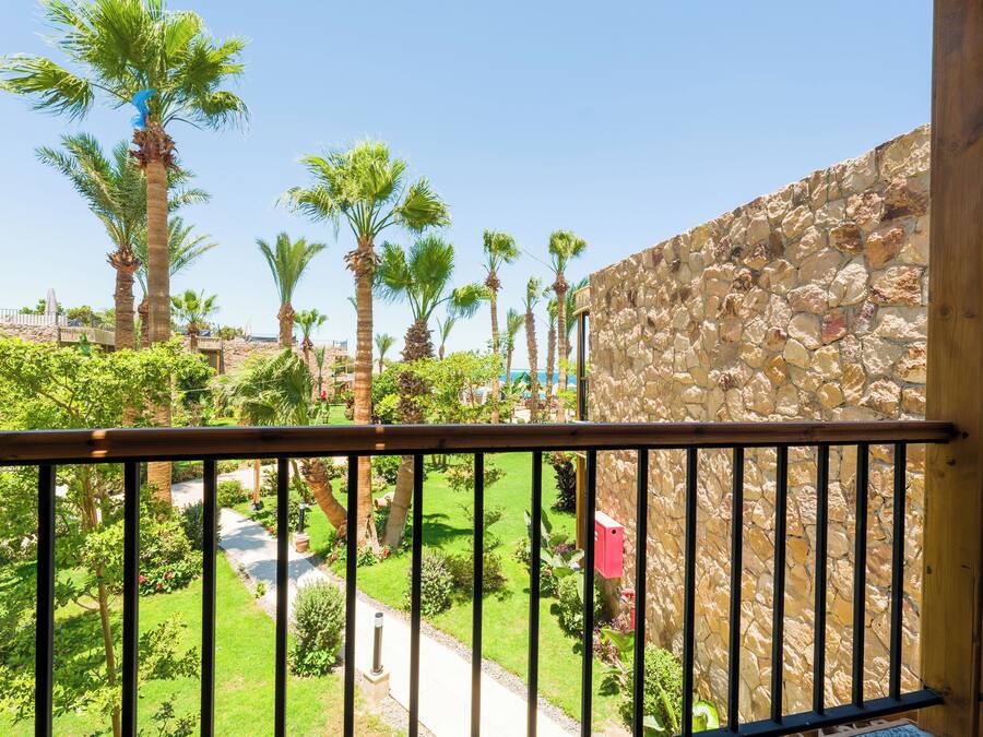A balcony with a stone wall and a pathway leading to a pool area.