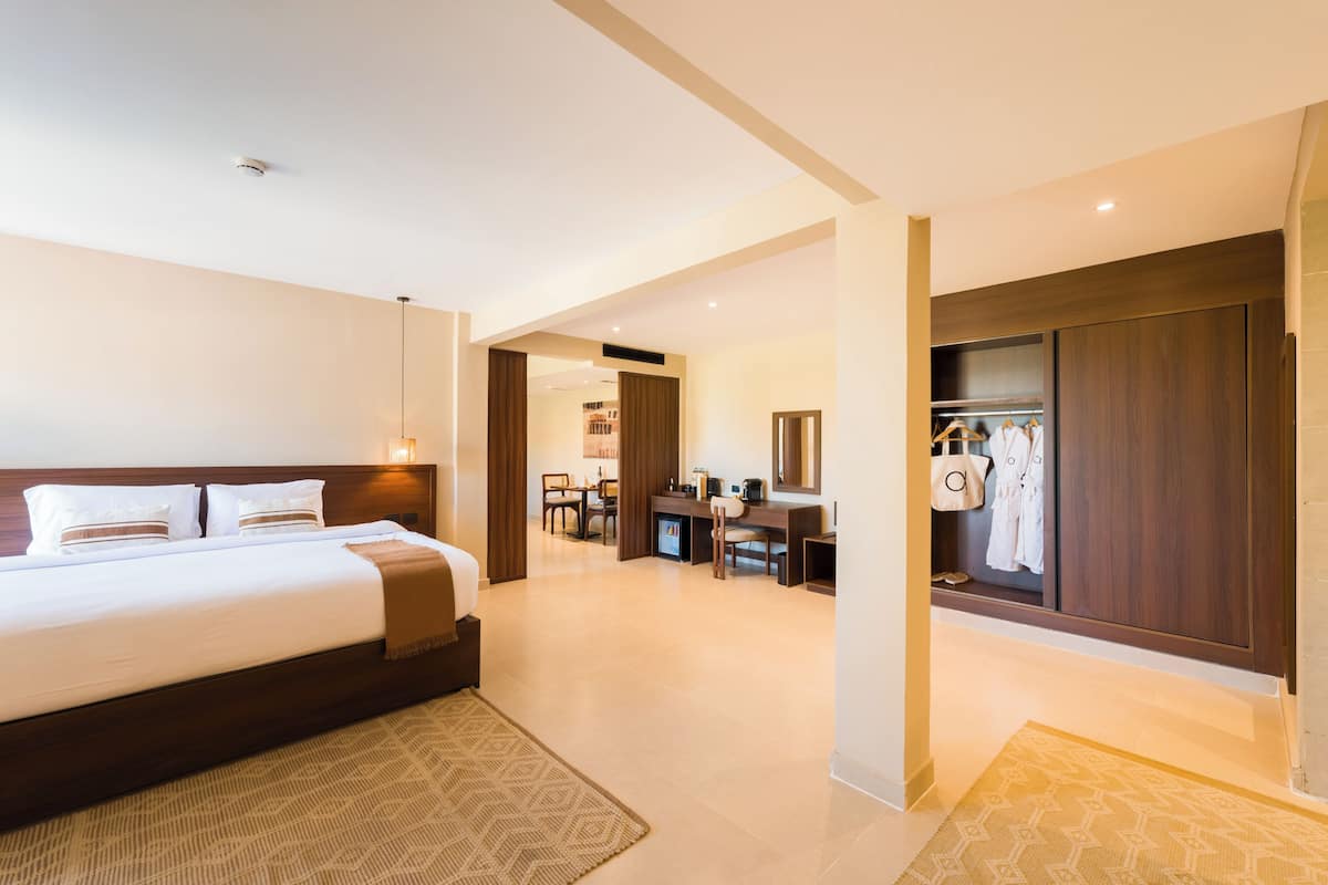 A hotel room with a large bed, a desk, and a wardrobe.