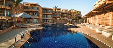 Un hotel con piscina, varios balcones y zonas de estar al aire libre.