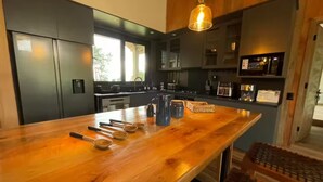 A modern kitchen with a wooden island, stainless steel appliances, and a hanging light fixture.