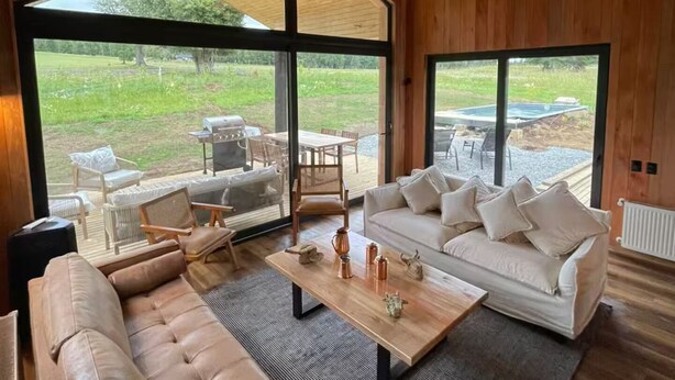 A spacious living room with a large window, a sofa, a coffee table, and a view of an outdoor patio area.