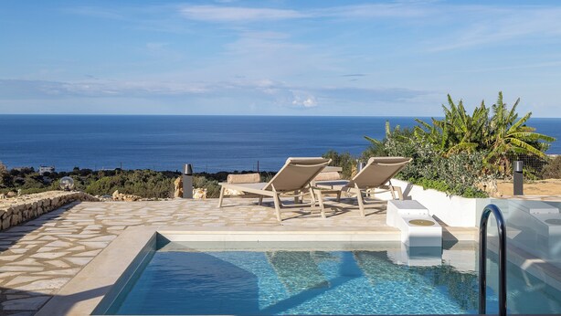 Une piscine avec des chaises longues et vue sur la mer.