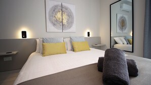 Een moderne hotelkamer met een net opgemaakt bed, twee nachtkastjes en een grote spiegel.