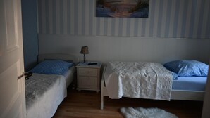 Una camera da letto con due letti, un comodino, una lampada e un quadro appeso al muro.
