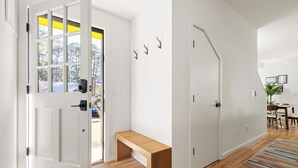 Un interior moderno con un banco de madera, paredes blancas y una puerta con detalles amarillos.