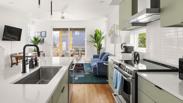 Cocina moderna con una isla central, electrodomésticos integrados y un comedor con vistas al exterior.