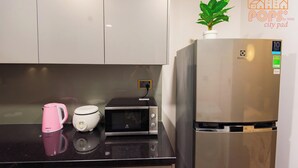 Een keuken met een koelkast, magnetron en een roze waterkoker op het aanrecht.