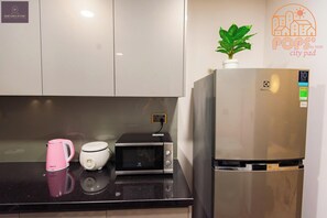 Eine Küche mit Kühlschrank, Mikrowelle und einem rosa Wasserkocher auf der Arbeitsplatte.