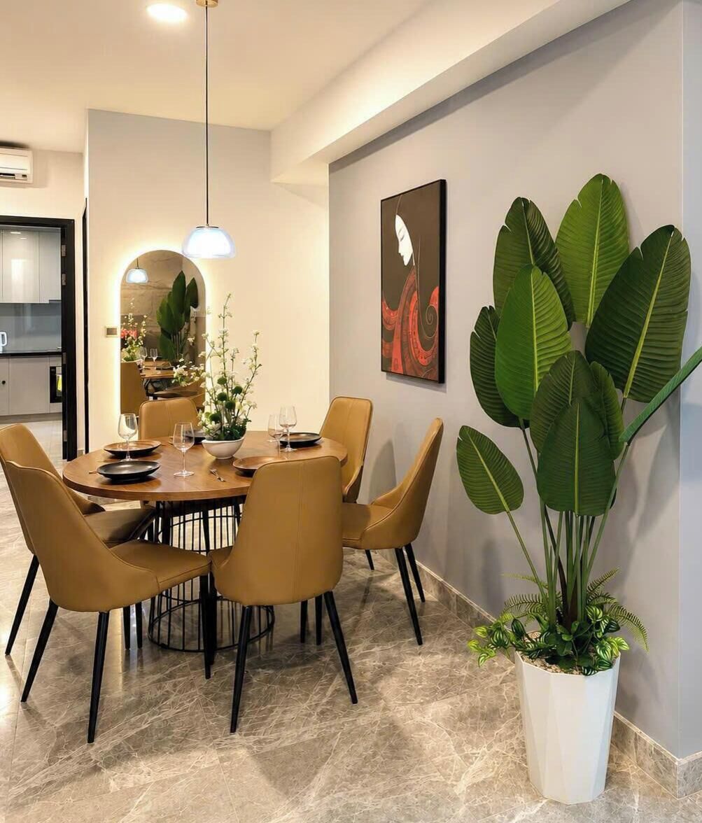 Un comedor con una mesa redonda, sillas y una planta en maceta.