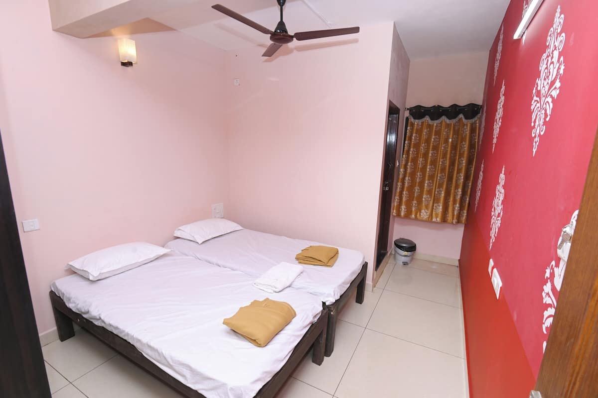 A room with two beds, a ceiling fan, a wall-mounted light, and a curtain.