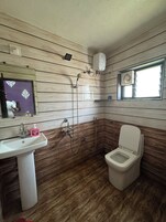 A bathroom with a sink, toilet, shower, and a window.