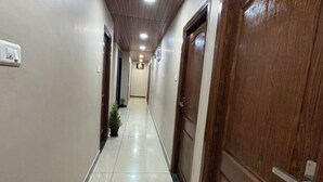 A hallway with wooden doors, a tiled floor, and a ceiling with recessed lighting. - Sri Sai Lodge Manipal (Udupi)