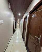 A hallway with wooden doors, a tiled floor, and a ceiling with recessed lighting.