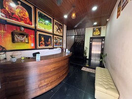 A reception desk with framed artwork, a wooden counter, and a black tiled floor.
