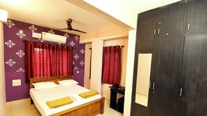 A bedroom with a bed, a wardrobe, a mirror, and an air conditioning unit. - Sri Sai Lodge Manipal (Udupi)