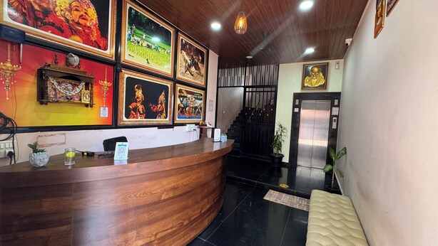 A reception desk with framed pictures, a staircase, and an elevator. - Sri Sai Lodge Manipal (Udupi)