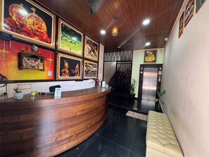 A reception desk with framed pictures, a staircase, and an elevator. - Sri Sai Lodge Manipal (Udupi)