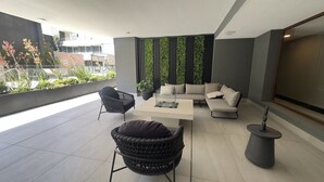A modern outdoor seating area with a sofa, chairs, and a table. - Oceana Suites Ñuñoa (Santiago)