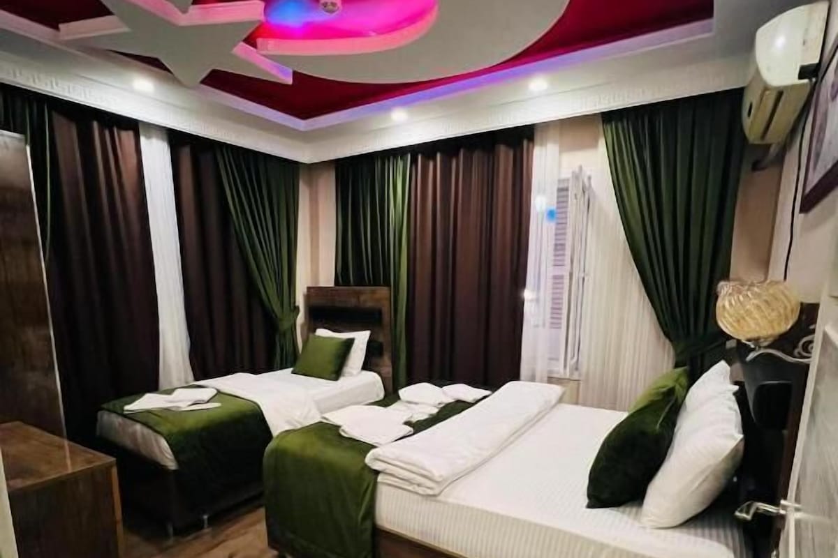 A hotel room with two beds, a ceiling with a unique design, and a wooden floor.