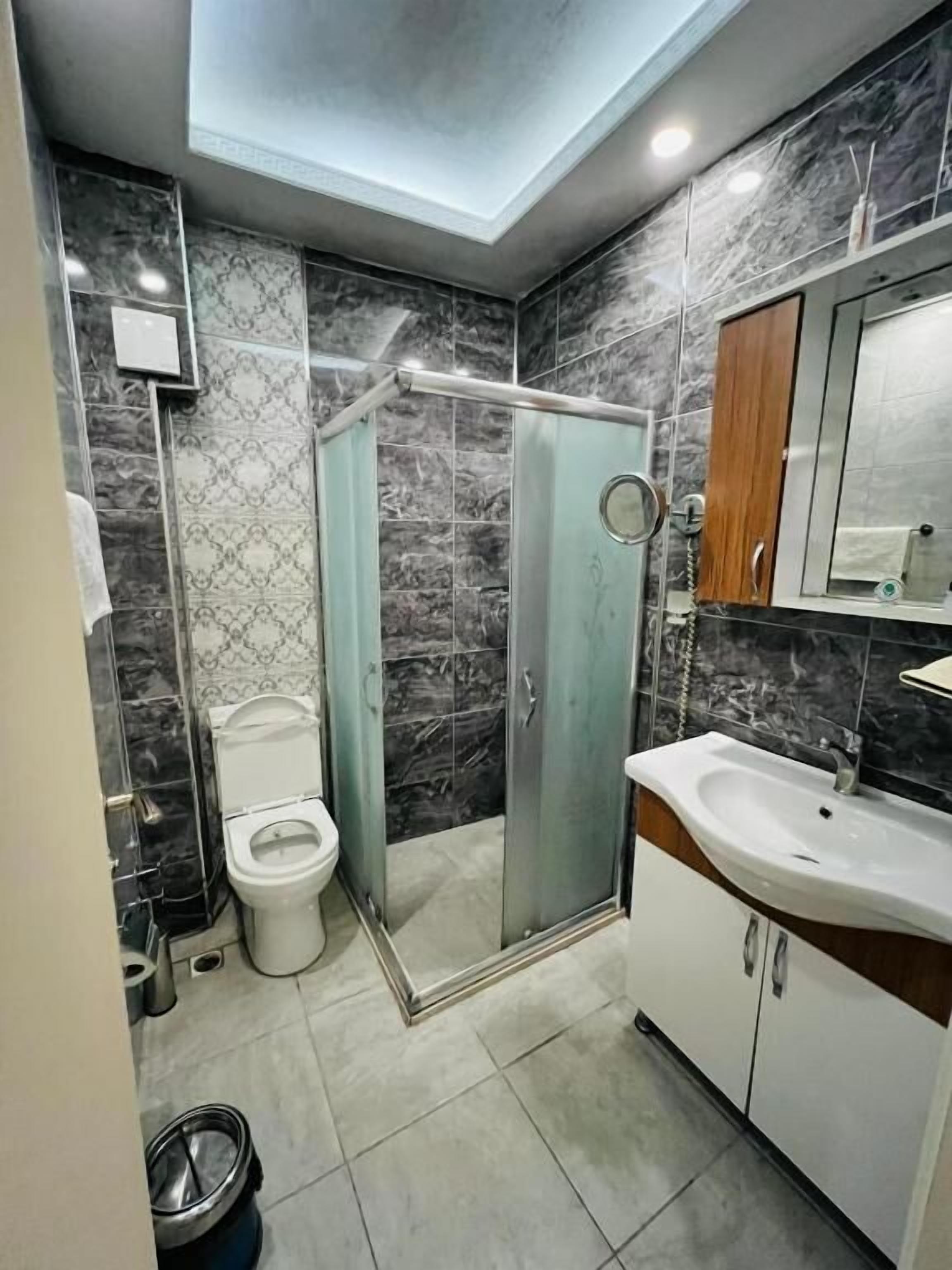 A compact bathroom with a glass-enclosed shower, a toilet, and a sink with a mirror above.