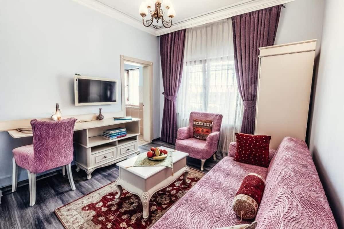 Ein Wohnzimmer mit einer Couch, einem Sessel und einem Schreibtisch mit Fernseher.