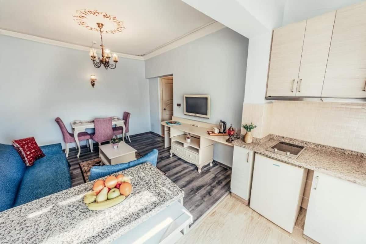 Ein gemütlicher Wohnbereich mit Küchenzeile, Essbereich und einer Sitzecke mit blauem Sofa und kleinem Tisch.