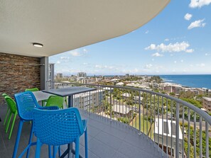 Ein Balkon mit Blick auf Stadt und Meer, ausgestattet mit einem Tisch und Stühlen.