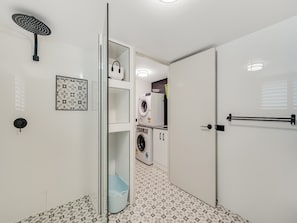 Casa de banho moderna com chuveiro, sanita e máquina de lavar roupa.