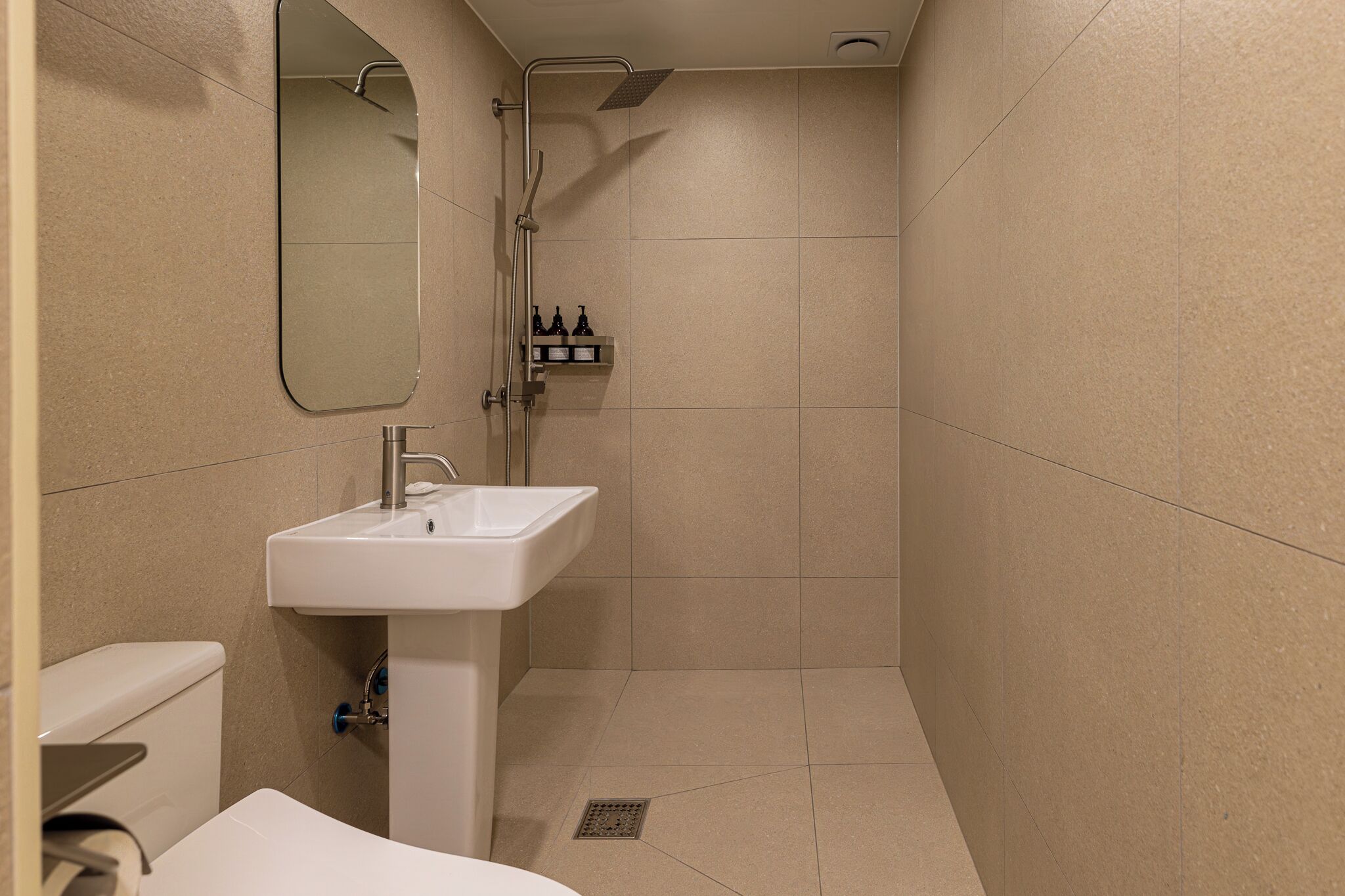A bathroom with a sink, mirror, shower, and toilet.