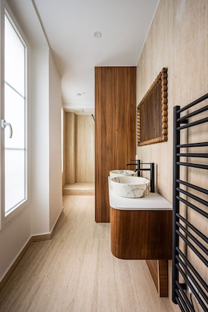 A modern bathroom with a wooden vanity, a marble sink, and a black towel rack. - Saint Germain des près - 2 chambres - rénové (Paris)