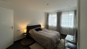 A hotel room with a bed, bedside tables, a desk, and a window with curtains. - Exclusive loft with fireplace & sun terrace near the trade fair directly at the train station & parking lot (Bad Salzuflen)