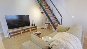 A living room with a large flat-screen TV, a sofa, a coffee table, and a bookshelf. - ON Apartments - Family - Free Parking & Pet Friendly (Porto)