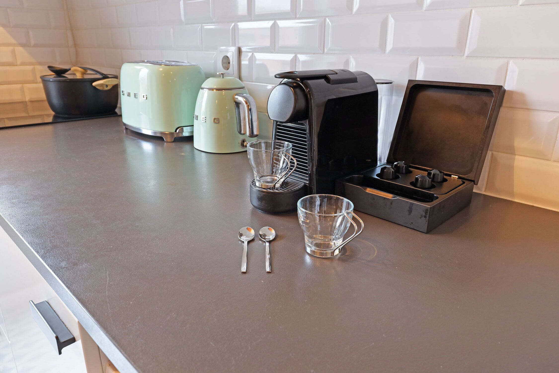 A kitchen counter with a coffee maker, a toaster, and a kettle.