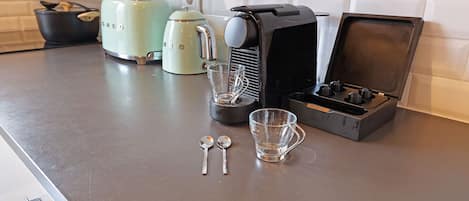 A kitchen counter with a coffee maker, a toaster, and a kettle.