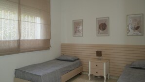 Une chambre à coucher avec un lit simple, une table de chevet et trois tableaux encadrés accrochés au mur.
